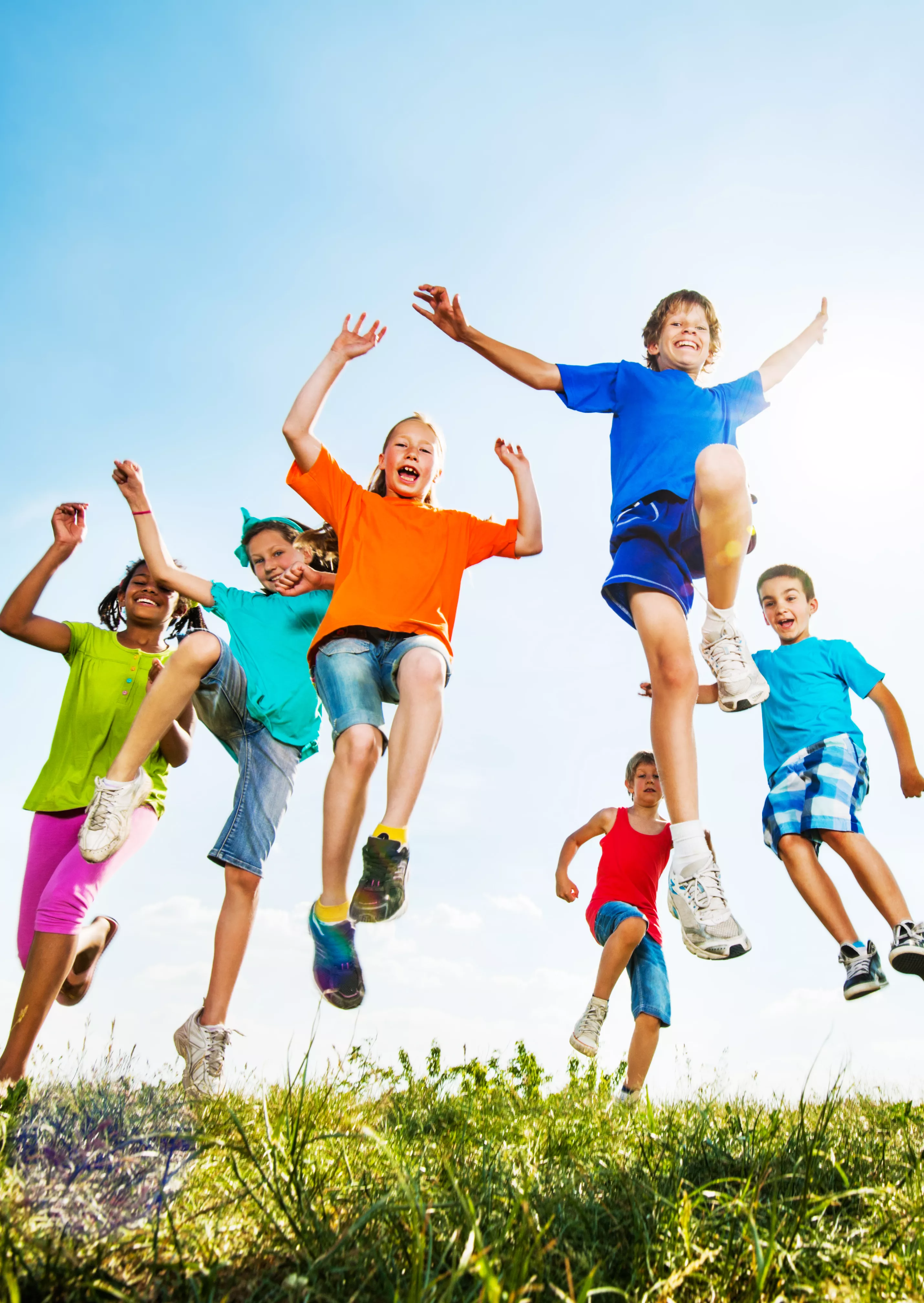 Enfants sautant de joie dans l'herbe sur fond de ciel bleu